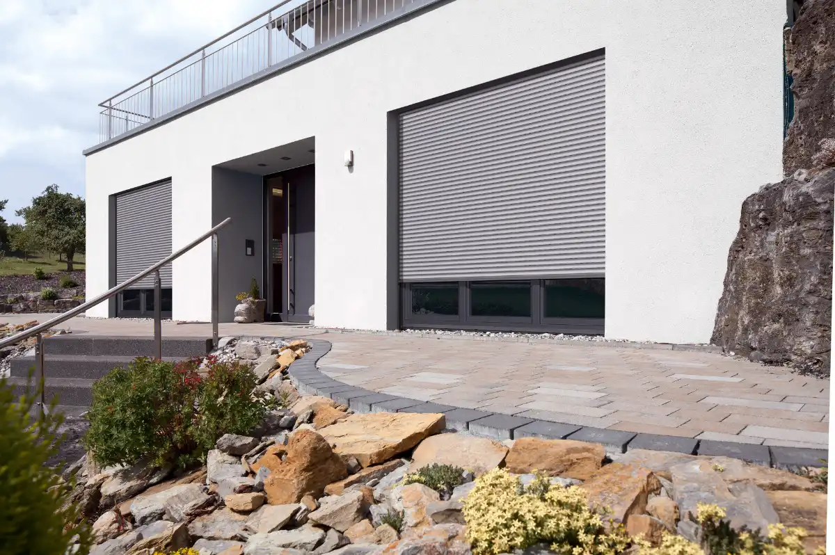 Moderne Hausfassade mit geschlossenen Rollläden und Steingarten