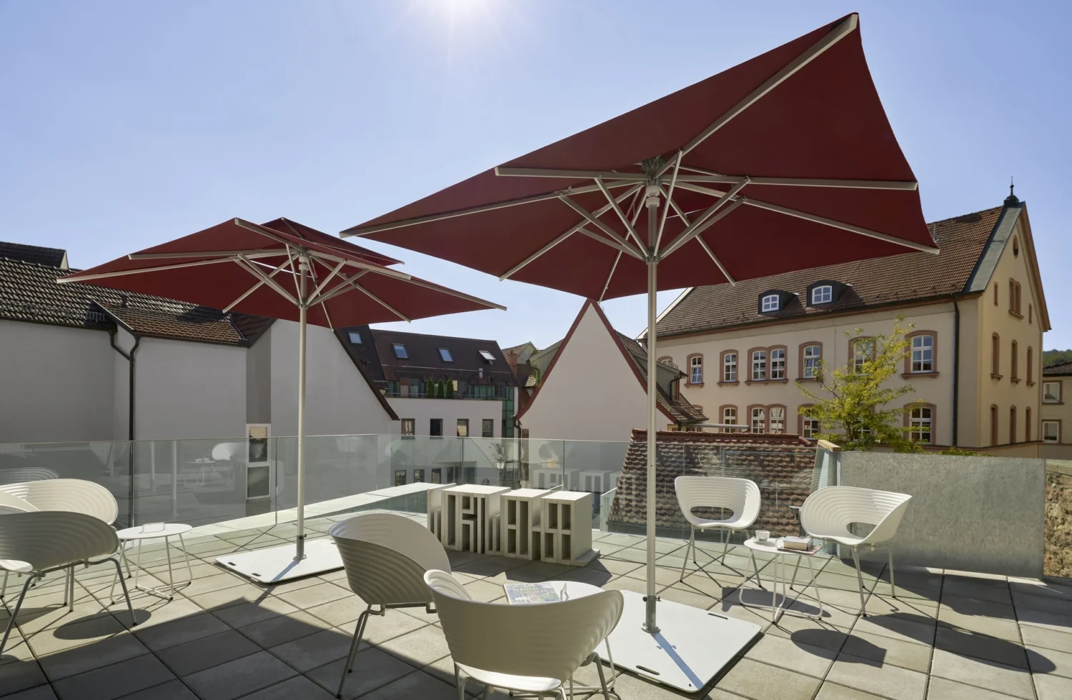 Eckiger roter Sonnenschirm auf moderner Dachterrasse