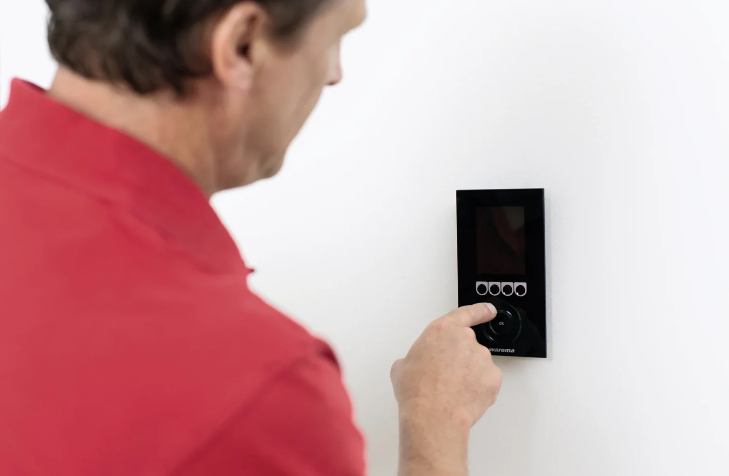 Mann bedient modernes Steuerungspanel an der Wand